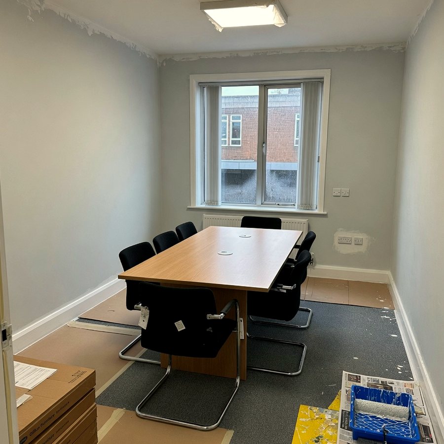 Office meeting room with newly painted walls, roller tray and protective cardboard